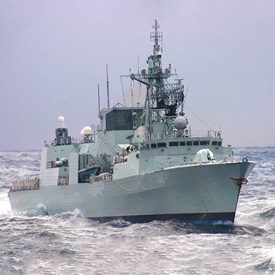 Military ship with UHF SATCOM communication systems navigating rough waters