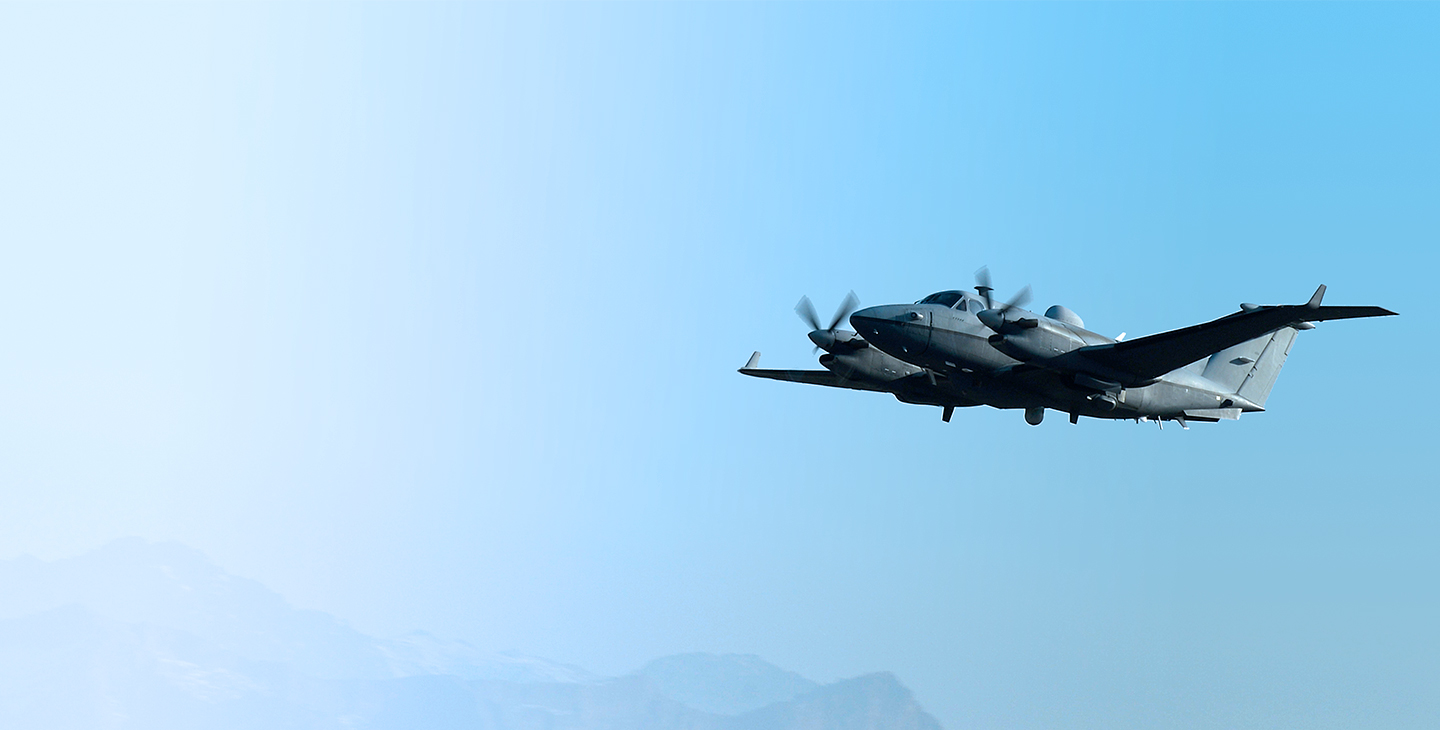 MC-12 Aircraft flying against a light blue sky