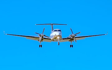 Private jet flying against a bright blue sky