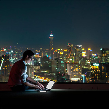 Person on laptop with city in background