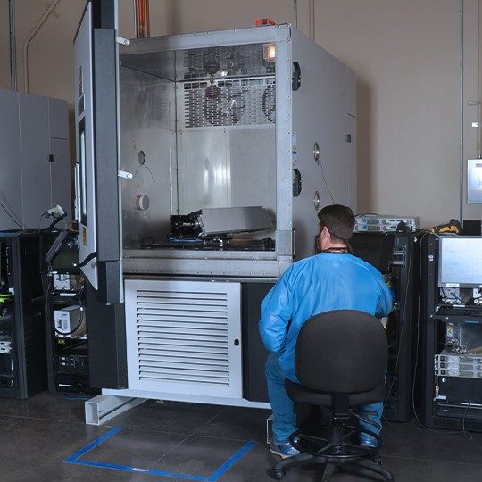 Man dressed in protective blue suit sitting in a chair performing antenna testing services