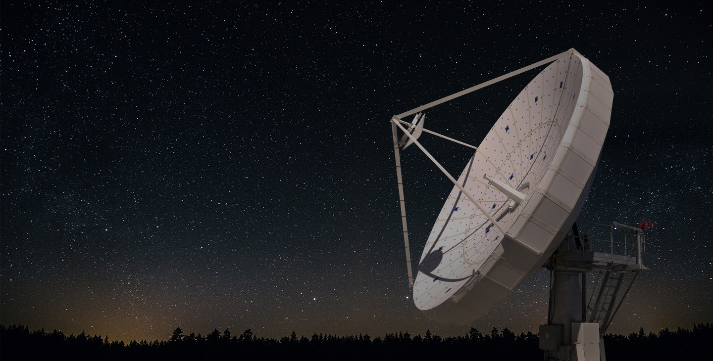 Large, white SATCOM antenna against a starry night sky