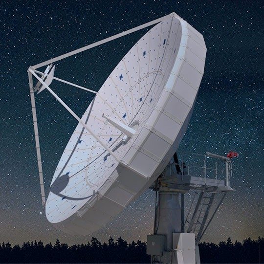Large ground antenna in front of stars across the night sky