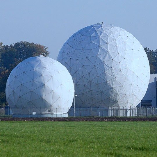 One large and one small radome containing isr systems, secured behind fencing