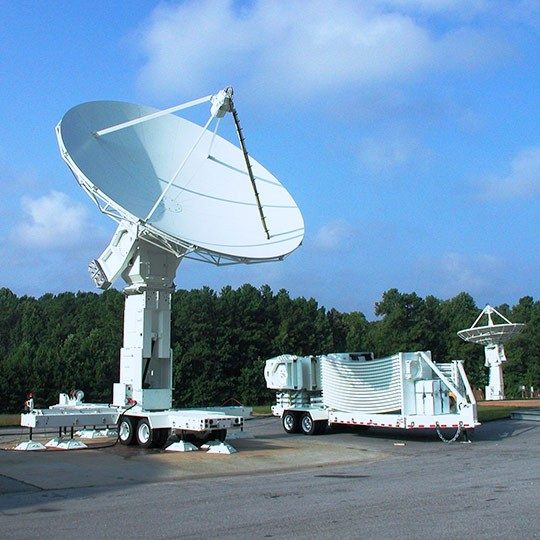 Large, white transportable antenna parked on pavement