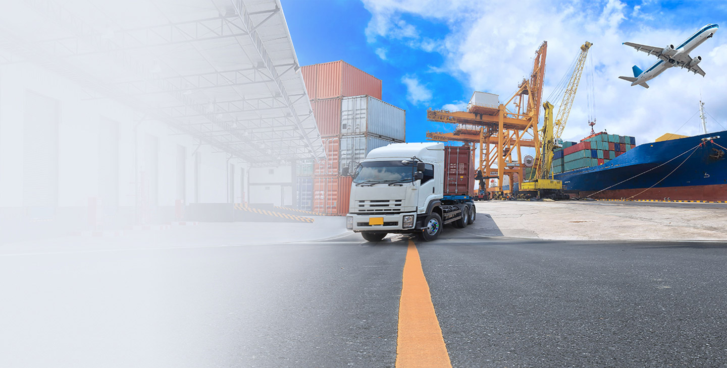 Truck parked on a dock next to cargo containers and a cargo ship with an airplane flying above