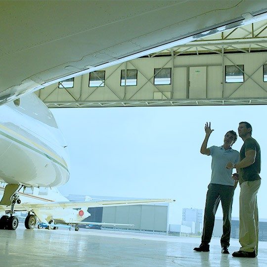 Two men standing beside a private jet discussing business aviation mro services