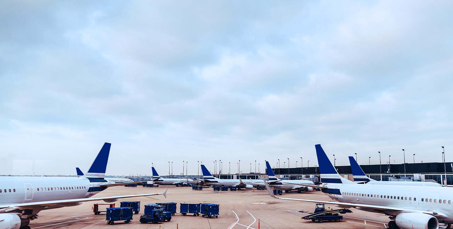 View of seven planes parked at their gates at an airport