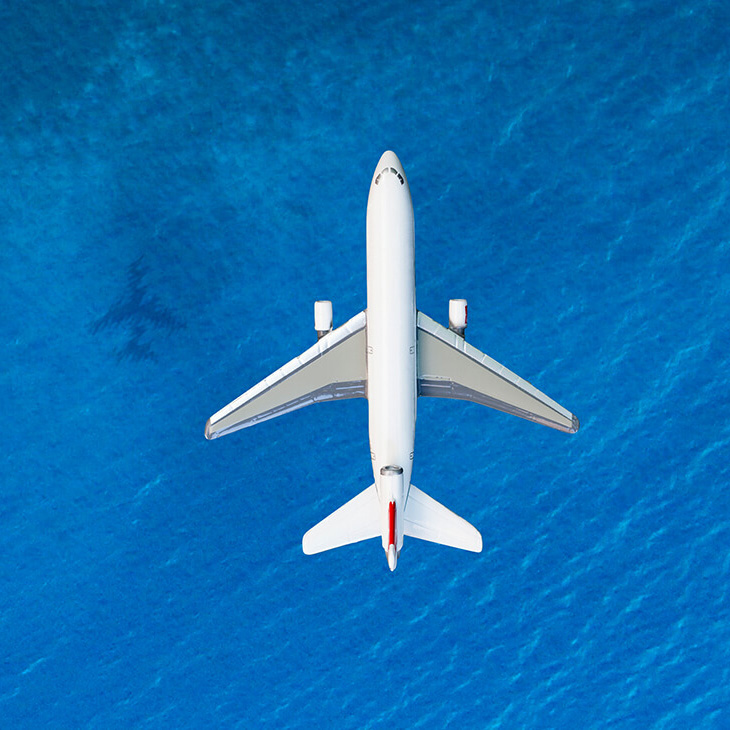 Commercial airplane flying over the osean casting a shadow on the water