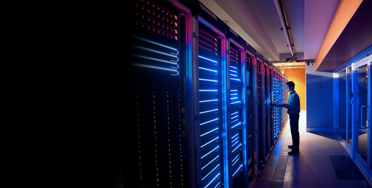 Man in plaid shirt working on a computer using a private cloud solution in a dimly lit server room