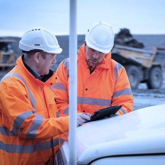 Direct cloud connect providing a private connection to two construction workers wearing orange jackets, looking at a tablet