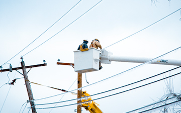 Two men in a bucket truck working on powerlines