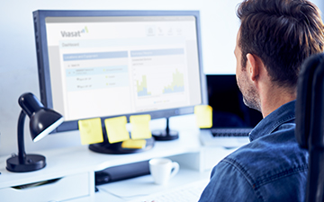 Man sitting at desk looking at his desktop monitor managing his Viasat business hotspot account