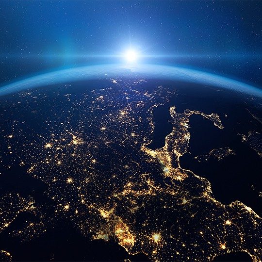View of the Earth from space, lit up at night with the sun on the horizon
