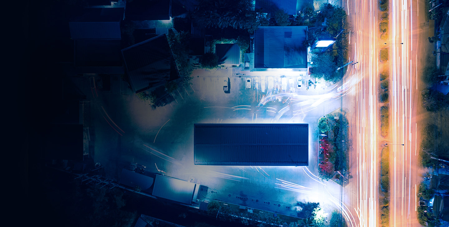 Arial view of a business at night with car lights streaming by on the street