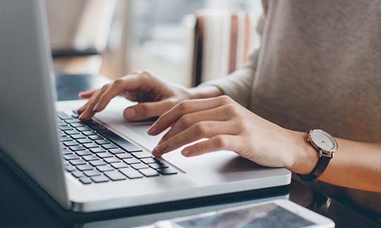 Close up image of hands typing on laptop
