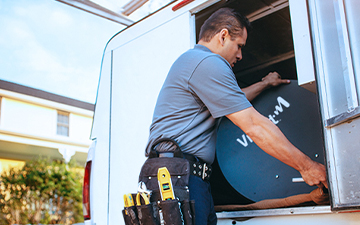 Viasat technician removing Viasat satellite dish from car trunk