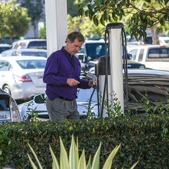 Man at electric vehicle charger for Corporate Sustainability at Viasat