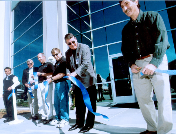 Mark Dankberg and five Viasat employees cutting a blue ribbon in front of the new Carlsbad, CA campus