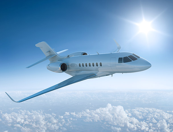 Private business jet flying above the clouds against a sunlit sky