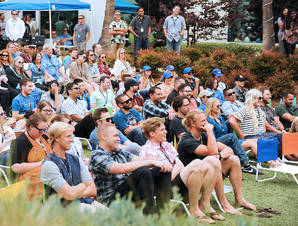 Gathering of Viasat employees seated in chairs in the courtyard in Carlsbad, listening to a presentation