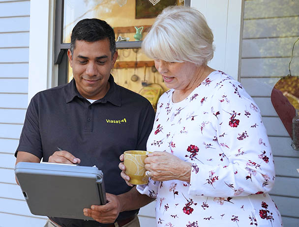 Viasat technician talking to a woman in front of her house