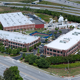 Aerial view of the Viasat campus in Deluth, Georgia with 3 office buildings, 7 satellite antennas and a tennis court