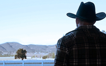 Home internet customer with cowboy hat looking out at the mountains