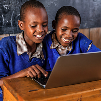 Two school boys in Africa smiling at a laptop