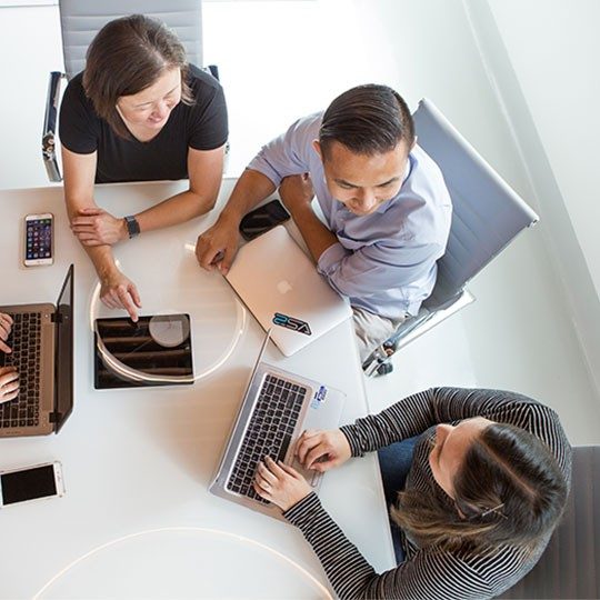 A group of employees working together at a conference table viewed from an overhead angle