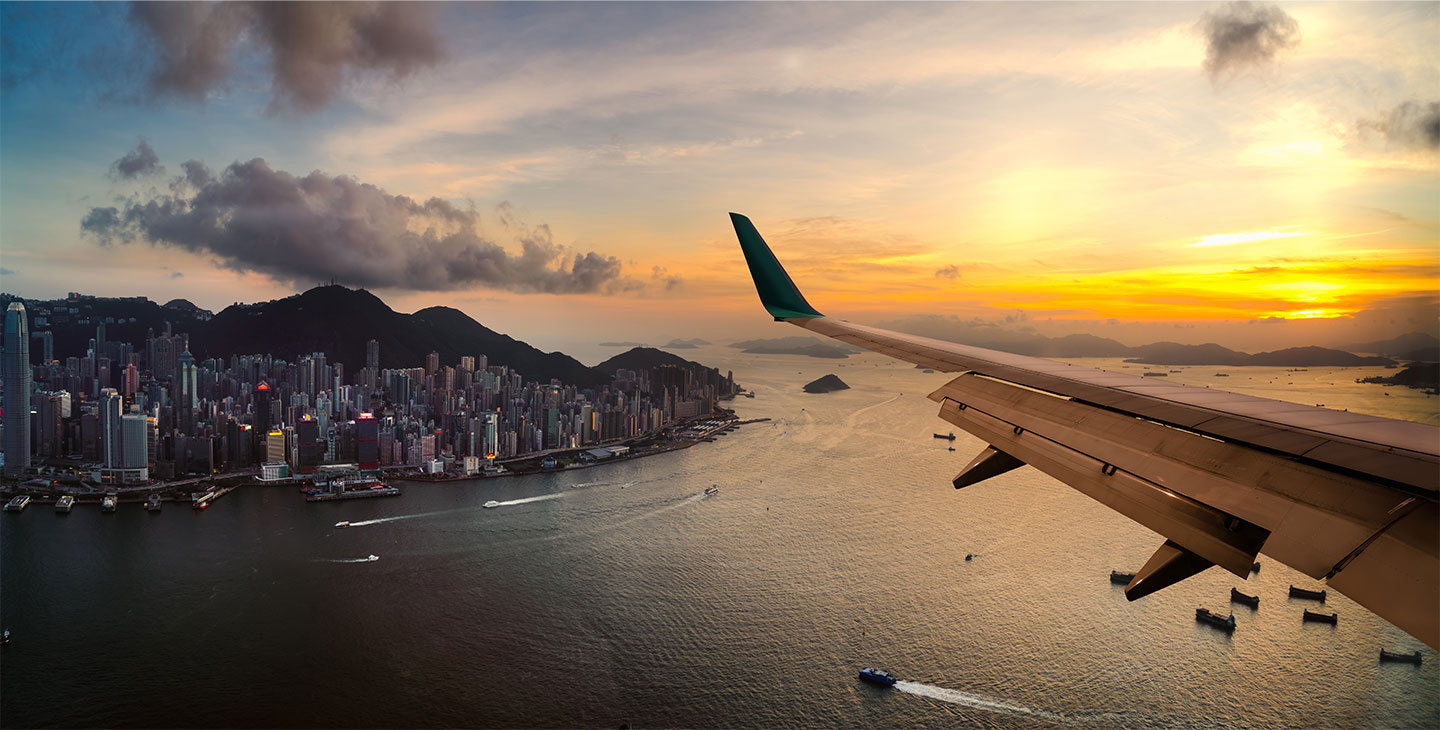 A plane flying over the ocean with a city on a peninsula in the distance - all connected by Viasat