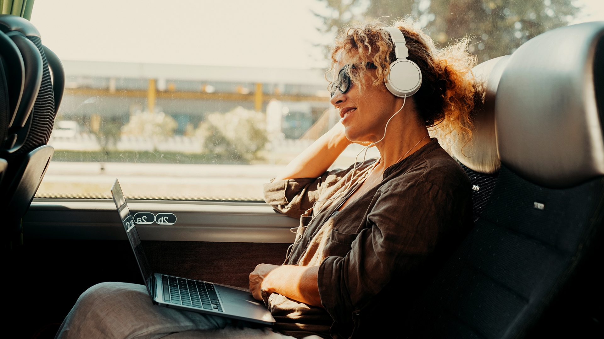 Mulher no ônibus com fones de ouvido e laptop