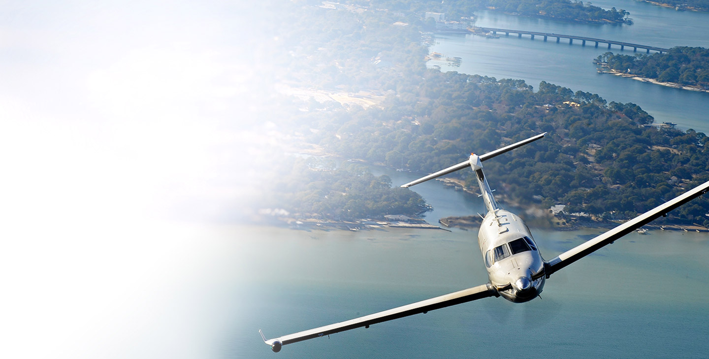 Top view of an aircraft flying over a body of water away from the coastline