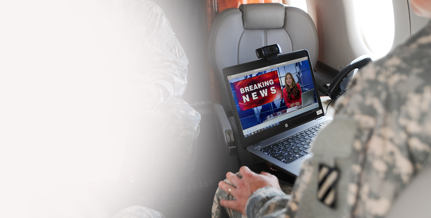 Senior leader on government aircraft equipped with aircraft technology, watching the news on laptop