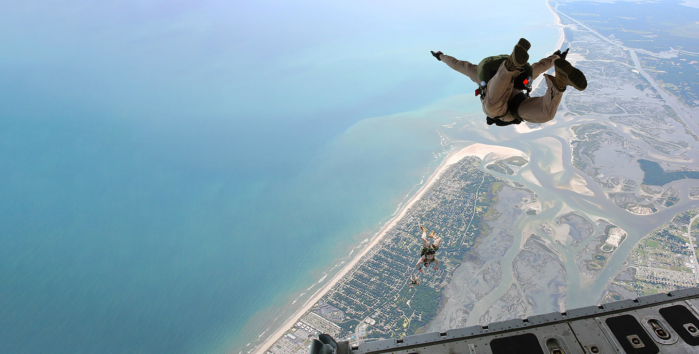 Warfighters with parachutes jumping out the back of a C-17 aircraft equipped with aircraft technology