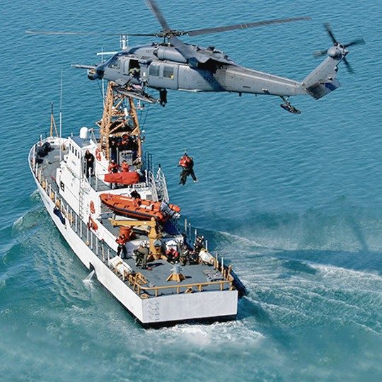 Helicopter and ship performing a search and rescue mission with a maritime terminal visible in the bow 