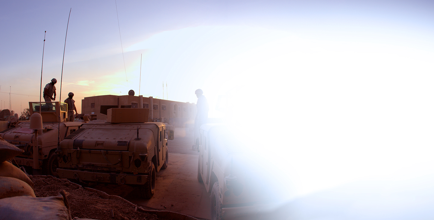 Military vehicles parked at a base at dusk