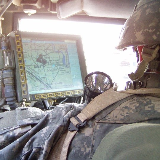 Soldier in a vehicle monitoring data from Blue Force Tracking program on a monitor