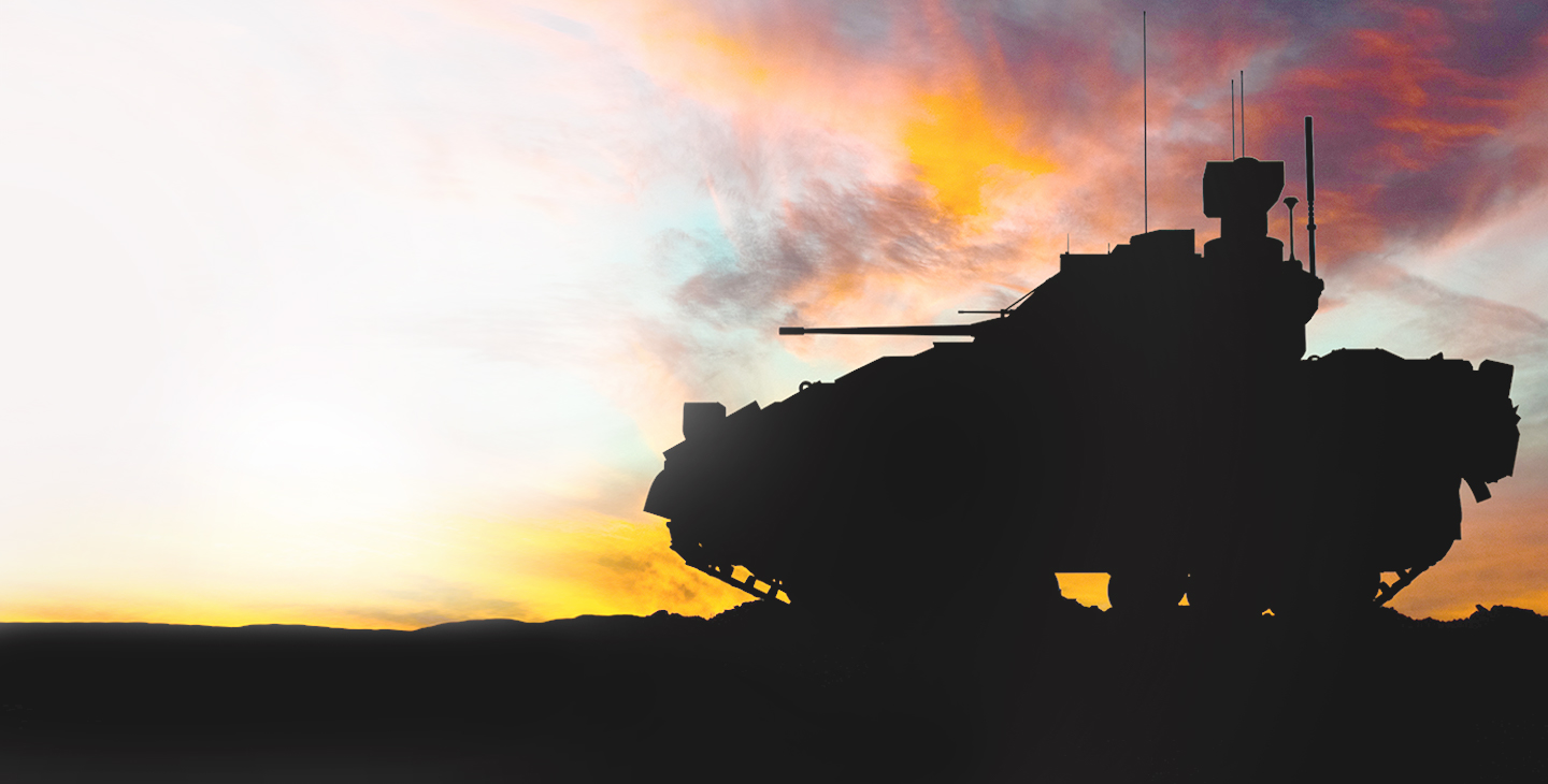 Silhouette of a military tank driving against the sunset