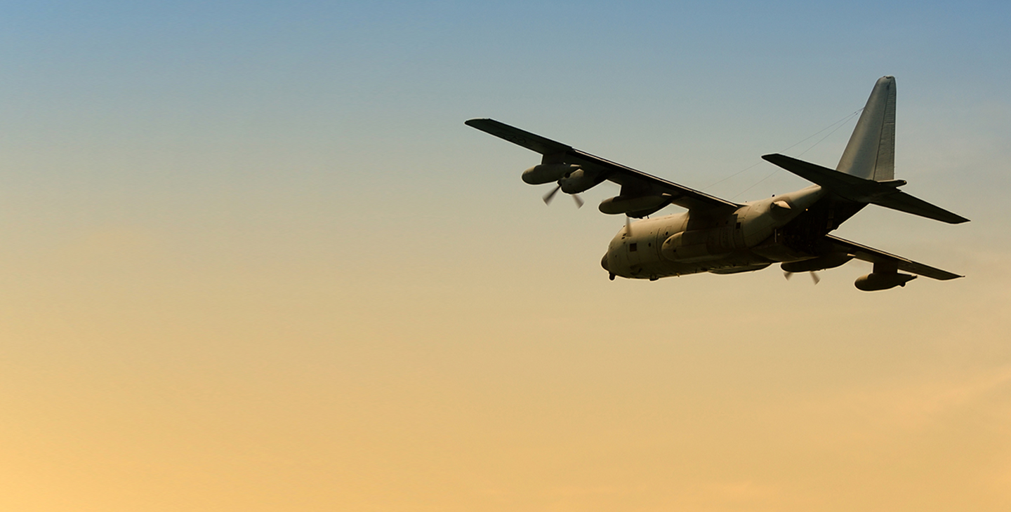 C-130 aircraft flying at dawn