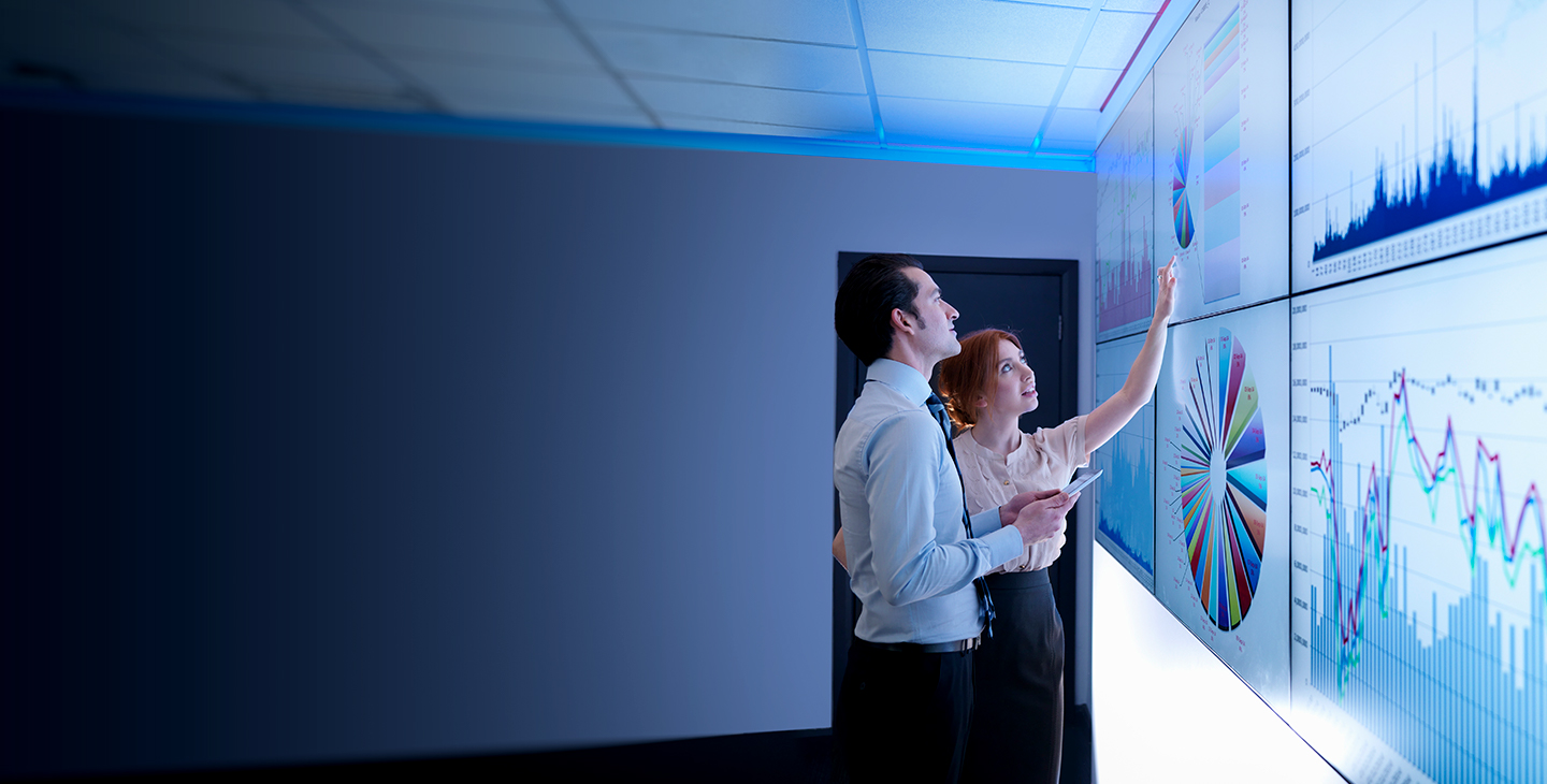 Man and woman discussing managed security data projected on the wall