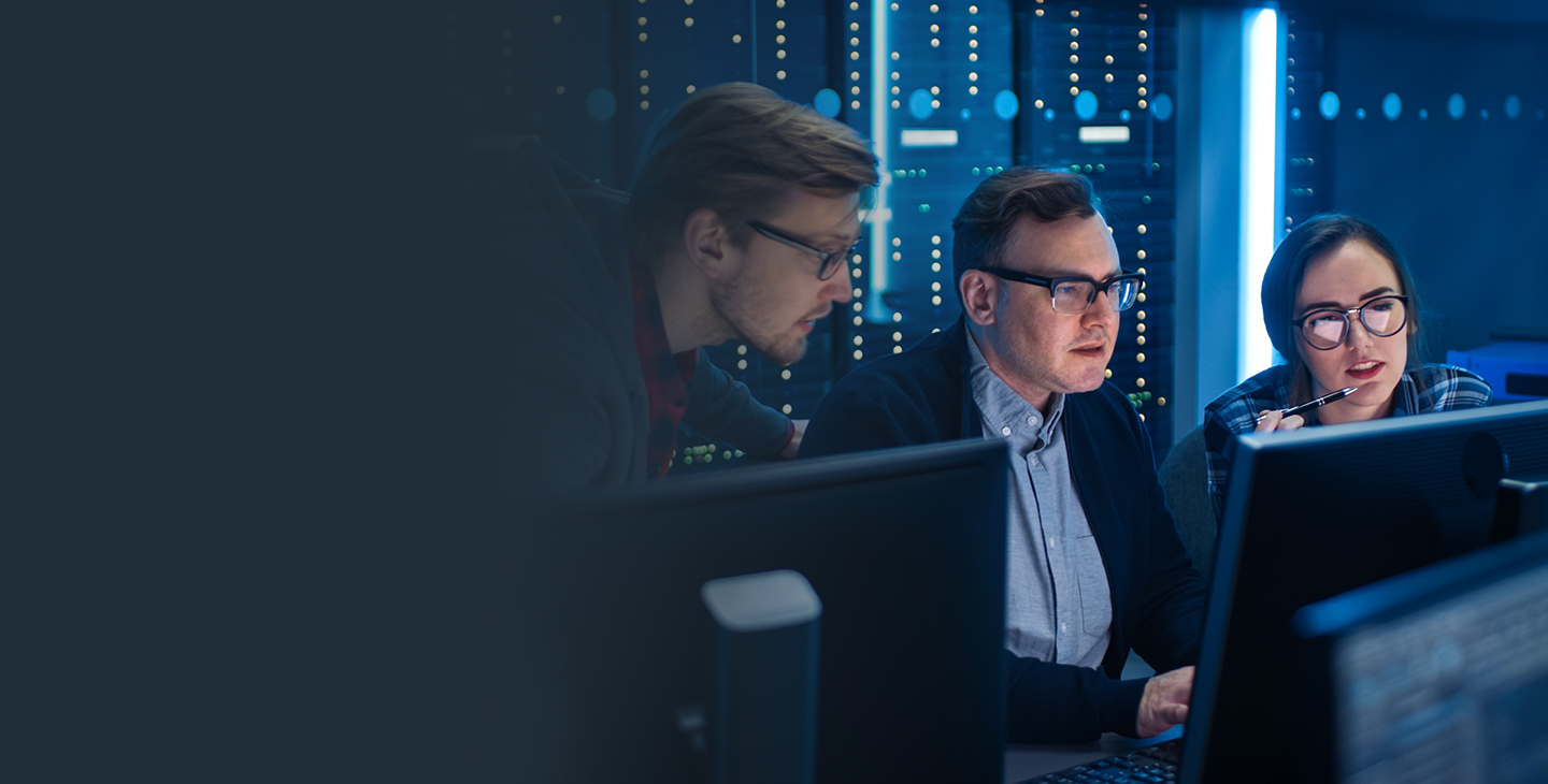 Two male and one female employees sitting behind computer monitors in a managed security room 