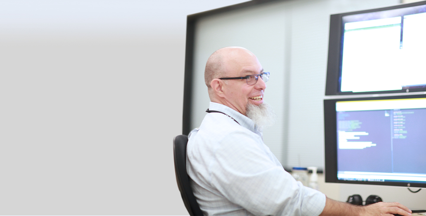 Viasat government service team member shitting at a computer looking over his shoulder and smiling