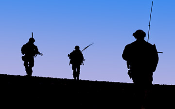Silhouettes of 3 solders againt the night sky