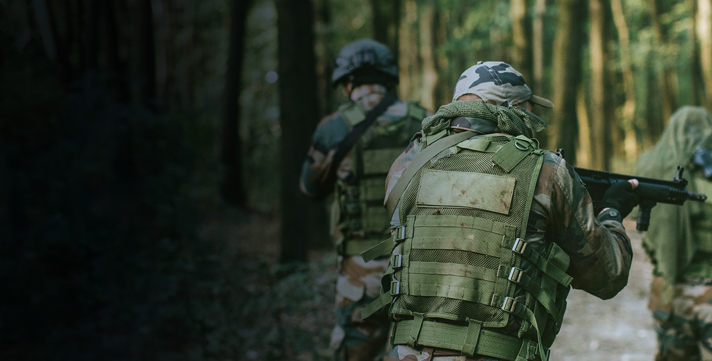 Two men dressed in camo gear with thier weapons drawn