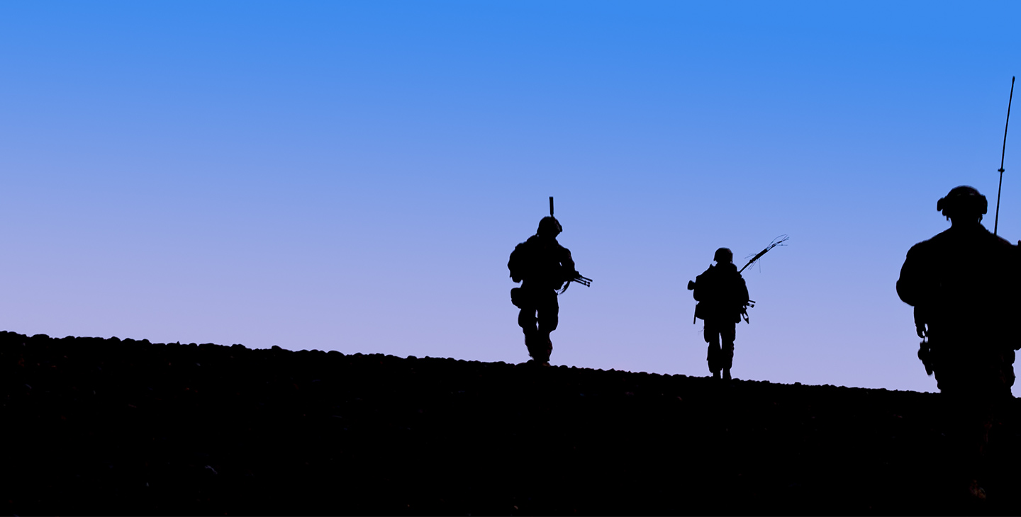 Silhouettes of three soldiers at dusk