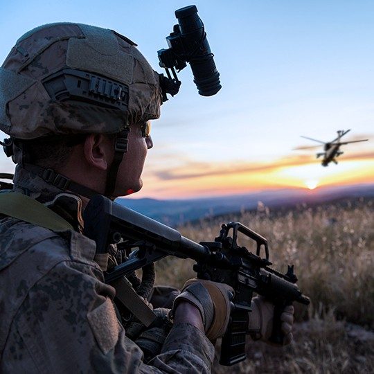 Warfighter standing and looking at helicopter flying away