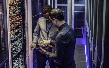 Two men in a server room looking at a tablet