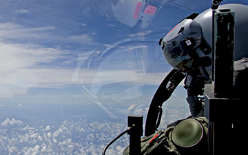 Fighter pilot looking out window of jet