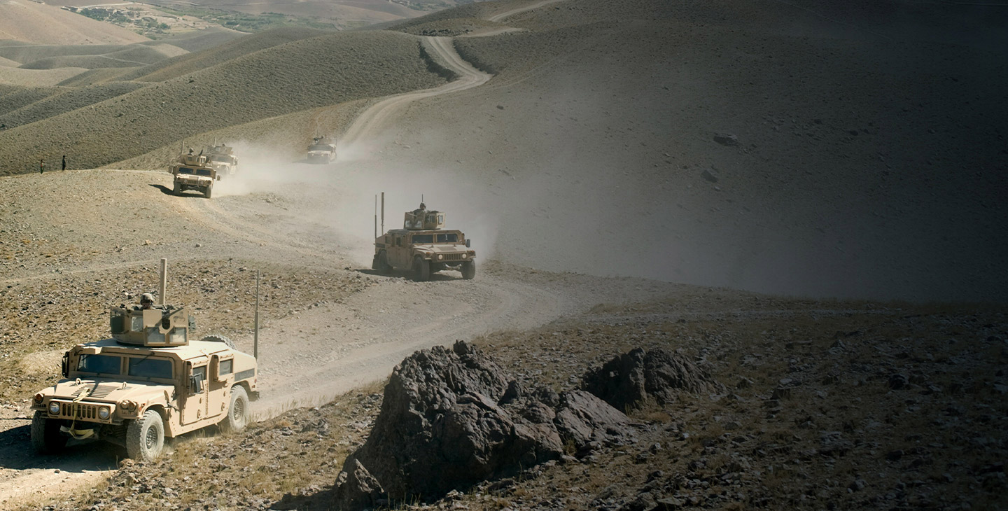 Five HUMVEEs driving on a dirt road